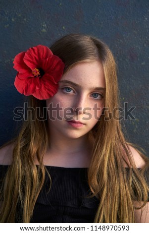 Blond kid girl portrait with hibiscus red flower on hair