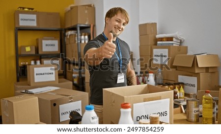 Blond man volunteering sorting donations in the storeroom giving thumbs up