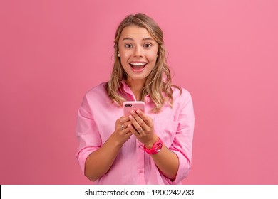 blond pretty woman in pink shirt smiling holding holding using smartphone posing on pink background isolated smiling having fun, emotional, excited - Powered by Shutterstock