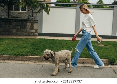 A blond teenage girl is taking her cute dog for a walk. - Powered by Shutterstock