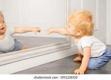 Blond toddler boy point to the mirror with finger