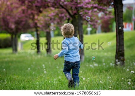 Similar – Adorable little girl playing with a ball sitting on a park bench