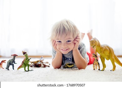 Blond Toddler Child, Playing With Dinosaurs At Home, Nice Soft Baclk Light