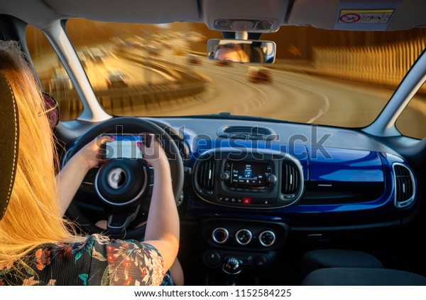 blond woman driving the car, at the\
same time who writes a text message on your\
smartphone