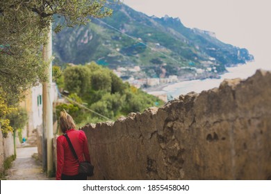 Blond Woman Hiking With Mediterranean Ocean On The Right And Mountains And Cities In The Background. 