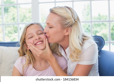 Blonde Frau küsst Tochter auf Wange zu Hause