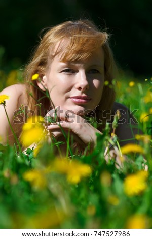 blond woman lies on the lawn with blooming dandelions