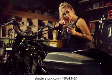 Blond Woman Mechanic Repairing A Motorcycle In A Workshop