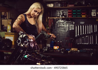 Blond Woman Mechanic Working In A Motorcycle Workshop