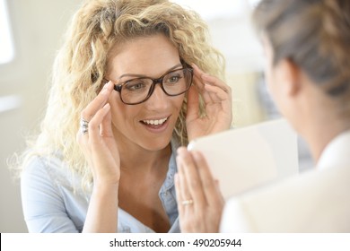 Blond woman at the optical shop, trying eyeglasses on