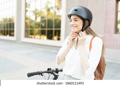 Blond woman putting on a safety helmet in order to use his alternative, eco-friendly vehicle to travel from her office to home 