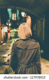 Blond Woman In Raincoat Walking Alone Outdoors At Night