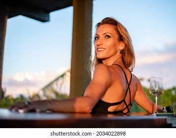 Blond Woman Smiling At Rooftop Bar Enjoying Sunset With Empty Glass Of Wine On A Sunny Day In Tulum, Quintana Roo, Mexico On October 15th 2020