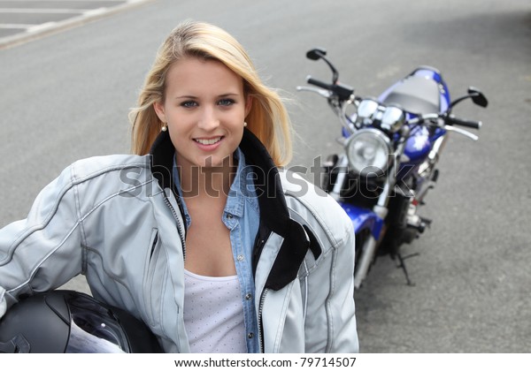 Blond woman stood by\
motorbike