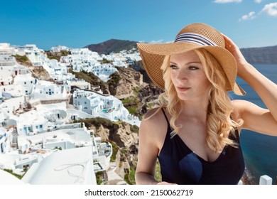 blond woman with a sun hat and a navy blue jumpsuit in Oia on Santorini. High quality photo