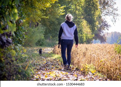 Blond Woman Walking Her Dog In A Trail At Fall