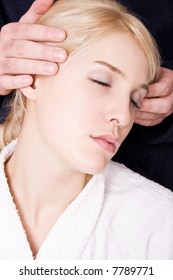 blond woman in white towel and mans hands massage her head