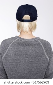 A Blond Woman(female, Girl) Wearing Black Cap And Grey Shirts Back Side Isolated White At The Studio.  