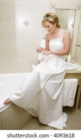 Blond young bride in sleeveless wedding dress with pearl detail and accessories getting ready in the bathroom