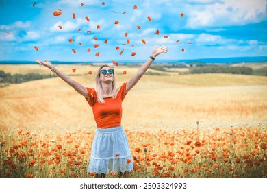 Blond young Caucasian woman in red white dress and sunglasses scatters red flower petals in the air in a field of poppies - Powered by Shutterstock