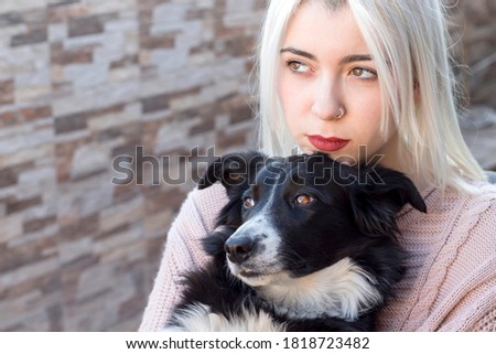 Blond young woman hugging her dog while sitting outdoors in a terrace