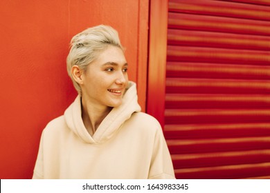 Blond young woman with short hair on the red background