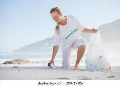 Blonde Activist Picking Up Trash On The Beach On A Sunny Day