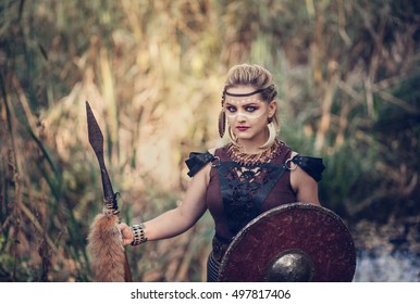 Blonde Amazon with a spear and a shield in the marshes in reeds