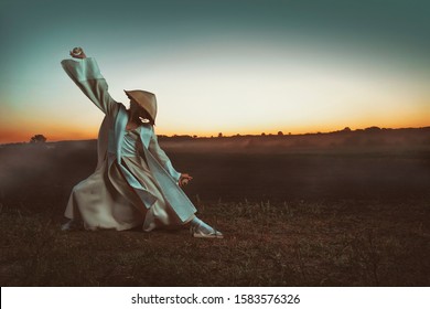 Blonde Asian woman with a long braid, doing martial arts in a field, in front of a sunrise, while holding wooden eggs - Powered by Shutterstock