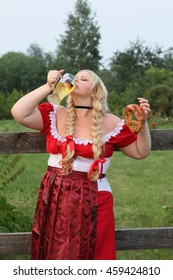Blonde bavarian female holding a Glass of Beer wearing a Dirndl