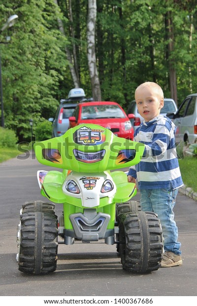 blonde boy goes for drive on electric quad bike. Tver\
Russia 2012. Sunny summer day. little girl rides his electric ATV\
quad. little boy of 5 years risk riding ATV quad bike in race\
track. quadbike 