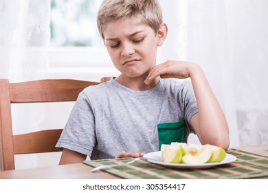 Blonde boy refusing to eat healthy apple