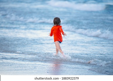 Blonde Boy Running And Having Fun On The Beach On Blue Sea In Summer