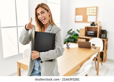 Blonde business woman at the office pointing fingers to camera with happy and funny face. good energy and vibes. 