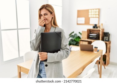 Blonde Business Woman At The Office Smelling Something Stinky And Disgusting, Intolerable Smell, Holding Breath With Fingers On Nose. Bad Smell 