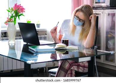 Blonde Business Woman Working On Quarantine From Home On The Kitchen Wearing Pijama And Protective Mask. Home Office Or Distance Learning Or Freelance Concept.Coffee Break.