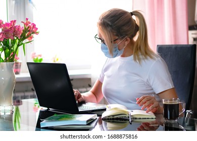 Blonde Business Woman Working On Quarantine From Home On The Kitchen Wearing Pijama And Protective Mask. Home Office Or Distance Learning Or Freelance Concept. Coffee Break.