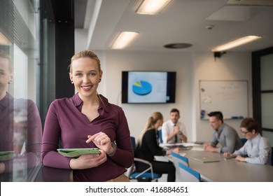 Blonde Businesswoman In Casual  Clothes Working On Tablet Computer At Modern Startup Business Office Interior. Young People Group On Team Meeting Blured  In Background