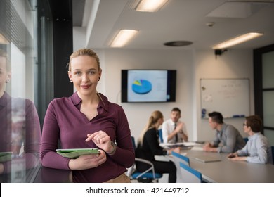 Blonde Businesswoman In Casual  Clothes Working On Tablet Computer At Modern Startup Business Office Interior. Young People Group On Team Meeting Blured  In Background