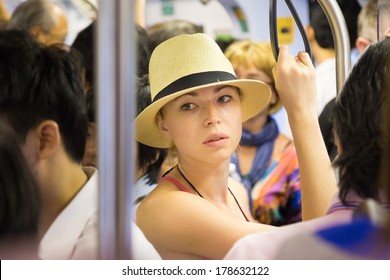 Blonde caucasian lady traveling by public transport. Lonely in the crowd.