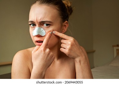 A blonde Caucasian woman getting rid of blackheads on her nose with a special plaster. beauty skin care concept.

Woman squeezes out pimples. 
