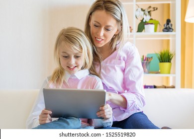 Blonde cheerful girl with her mother using tablet computer together
