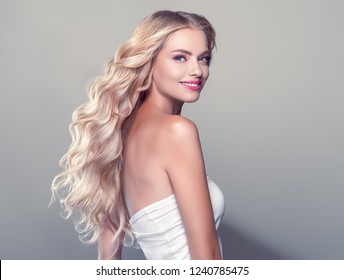 Blonde curly long hair woman with beauty makeup over gray background