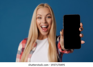 Blonde Excited White Woman Smiling While Showing Mobile Phone Isolated Over Blue Background