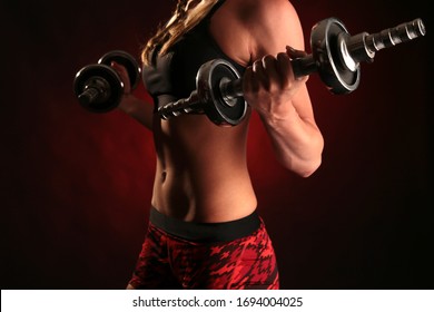 A Blonde Female Athlete With Boxer Braids Lifts Dumbbells In Training