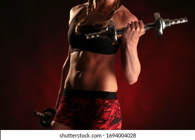 A Blonde Female Athlete With Boxer Braids Lifts Dumbbells In Training