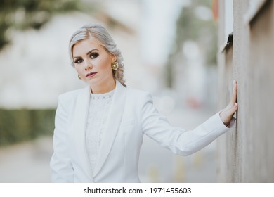 A Blonde Female Posing In An Elegant White Pantsuit