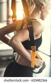 Blonde fitness woman training with trx fitness straps