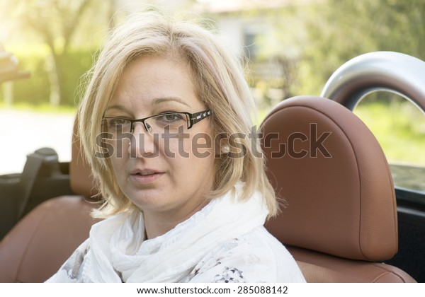 Blonde forty\
years old woman in cabriolet car\
