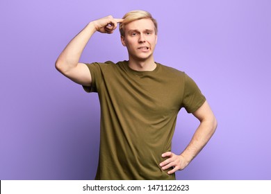 Blonde Frustrated Angry Sad Man With Hand On His Hip Points At Head. Close Up Photo. Isolated Violet Background.guy Doesn't Agree With His Friend. Are You Mad Are Your Stupid